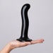Hand holding a black silicone dildo with a curved shaft and suction cup base against a plain background.