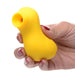 Hand holding a compact yellow silicone clitoral stimulator with a rounded suction tip.