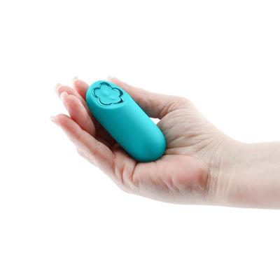 Teal mini bullet vibrator with flower-shaped control buttons held in a hand against a white background.