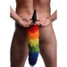 Rear view of a person holding a black silicone butt plug with a long, fluffy rainbow-colored faux fur tail.