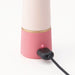 Close-up of Tenga Iroha Rin+ SANGO vibrator charging with a black USB cable connected to its pink base.