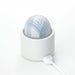 Tenga Iroha Temari Mizu in white and blue with floral design, shown in a white charging dock with USB cable attached.