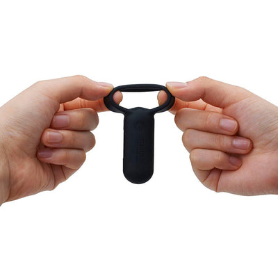 Hands holding and stretching a black silicone vibrating ring with a compact control unit.