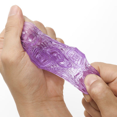 Close-up of hands stretching a translucent purple textured Tenga Uni sleeve, showcasing its flexible material and intricate design.