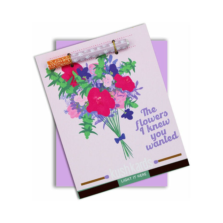 Greeting card with colorful floral illustration and attached metal one-hitter pipe featuring cannabis leaf design.