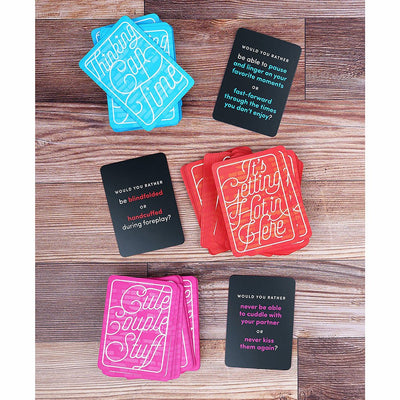 Colorful "Would You Rather?" cards for couples with categories like Thinking Cap Time, It's Getting Hot in Here, and Cute Couple Stuff on a wooden surface.