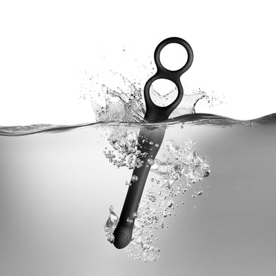 The-vibe Black/silver flexible male strap and anal stimulator submerged in water with bubbles, highlighting its waterproof design.