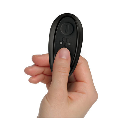 Hand holding a small black remote control with a single button for The-vibe Black/silver stimulator.