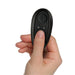Hand holding a small black remote control with a single button for The-vibe Black/silver stimulator.