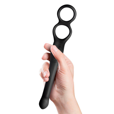 Hand holding The-vibe Black/silver flexible male strap and anal stimulator with dual rings and slender shaft.