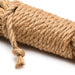 Close-up of natural undyed jute bondage rope coiled with a knotted end on a white background.