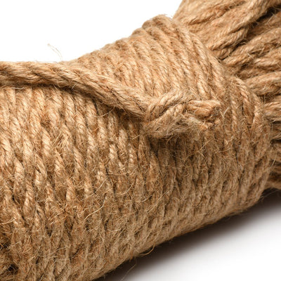 Close-up of natural undyed jute bondage rope tightly coiled with a tied knot on a white background.