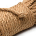 Close-up of natural undyed jute bondage rope tightly coiled with a tied knot on a white background.