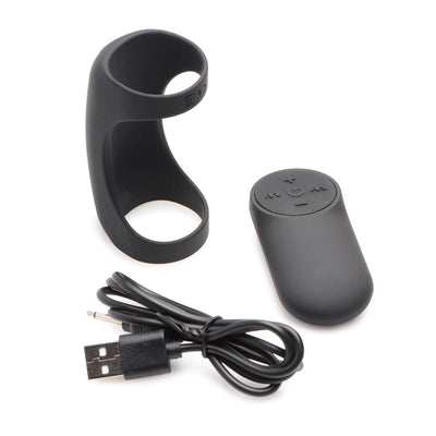 Black silicone vibrating shaft ring with remote control and USB charging cable on white background