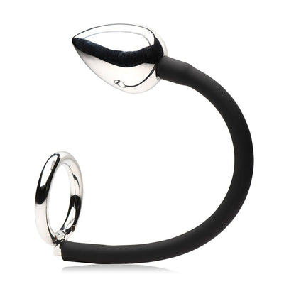 Metal anal plug connected by a black silicone cord to a metal cock and ball ring.