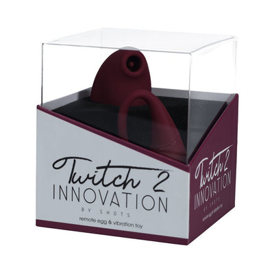 Twitch 2 rechargeable remote-controlled vibrator and suction toy in burgundy, displayed in clear retail packaging.
