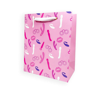 Pink gift bag with playful vibrator and handcuff illustrations, white ribbon handles, and gold grommets.