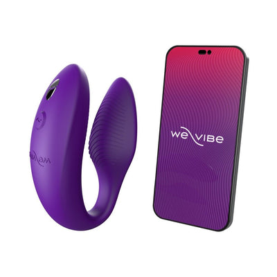 Purple We-Vibe Sync couples vibrator next to smartphone displaying We-Vibe app interface on white background.