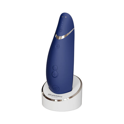 Womanizer Premium 2 clitoral stimulator in blueberry blue with charging stand on white background