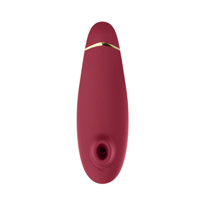 Womanizer Premium 2 clitoral stimulator in deep red with gold accent and silicone suction head, sleek ergonomic design.
