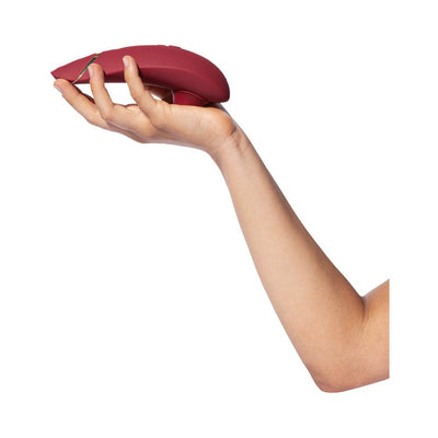 Hand holding a sleek Bordeaux Womanizer Premium 2 clitoral stimulator with ergonomic design.