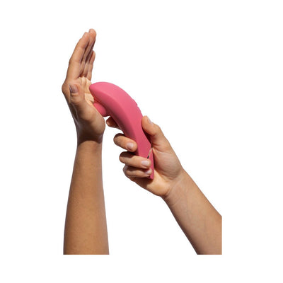 Hands holding a pink Womanizer Premium 2 clitoral stimulator demonstrating its ergonomic design.