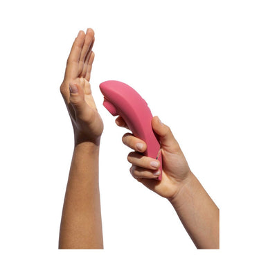 Hands holding a pink Womanizer Premium 2 clitoral stimulator against a white background.