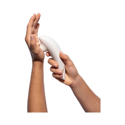 Hands holding a white Womanizer Premium 2 clitoral stimulator demonstrating its ergonomic design.