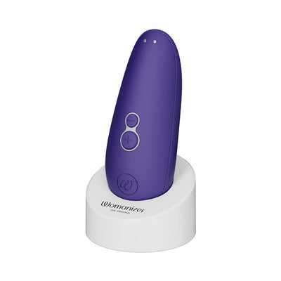 Purple Womanizer Starlet 3 clitoral stimulator standing on a white charging base with control buttons visible.