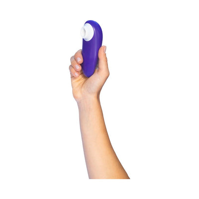 Hand holding a compact Womanizer Starlet 3 clitoral stimulator in violet with a white silicone head.