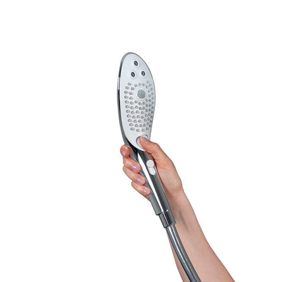Hand holding the sleek chrome Womanizer Wave Shower Head Masturbator with silicone nozzles and control button.