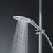 Sleek chrome Womanizer Wave shower head releasing a fine spray of water, mounted on adjustable shower rail with hose.