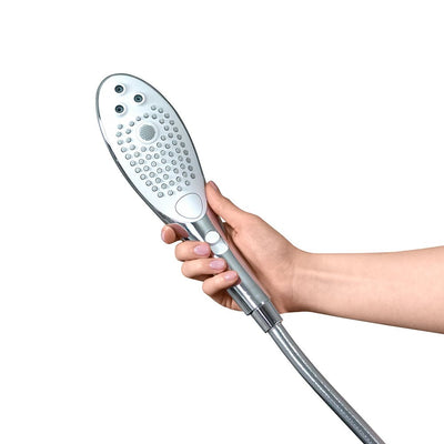 Hand holding a sleek silver and white Womanizer Wave shower head with multiple spray nozzles and control buttons.