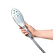 Hand holding a sleek silver and white Womanizer Wave shower head with multiple spray nozzles and control buttons.