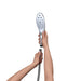 Hands holding and connecting the Womanizer Wave Shower Head Masturbator to a shower hose on a white background.