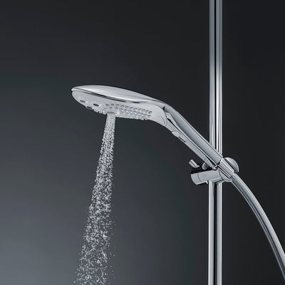 Sleek chrome Womanizer Wave shower head with water flowing, mounted on adjustable shower rail against dark background.