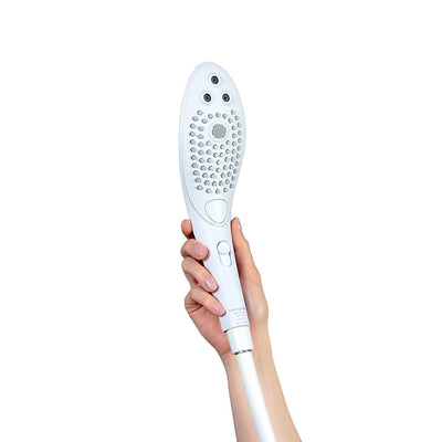 Hand holding the white Womanizer Wave shower head and clitoral stimulator with ergonomic design and multiple nozzles.