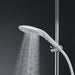 White Womanizer Wave shower head with water flowing, mounted on chrome shower rail against dark background.