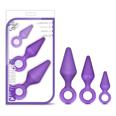 Set of three purple silicone anal training plugs in small, medium, and large sizes with ring handles, displayed with packaging.