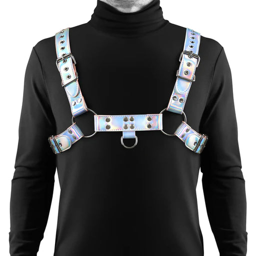 Man wearing a rainbow-colored adjustable chest harness with silver hardware over a black turtleneck shirt