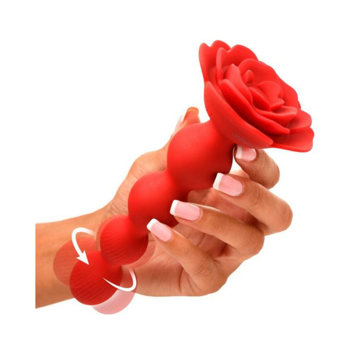 Hand holding red silicone anal beads with rose-shaped handle and rotating textured beads.