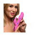 Woman holding a pink silicone rabbit vibrator with thrusting and vibrating features indicated by arrows and vibration lines.