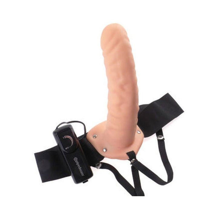 Adjustable flesh-colored vibrating hollow strap-on with black elastic harness and remote control on white background.