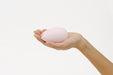 Hand holding a compact, smooth pink Tenga Iroha Massager with an ergonomic, rounded shape.