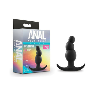 Black silicone anal plug with three tapered beads and curved base next to its colorful packaging box.