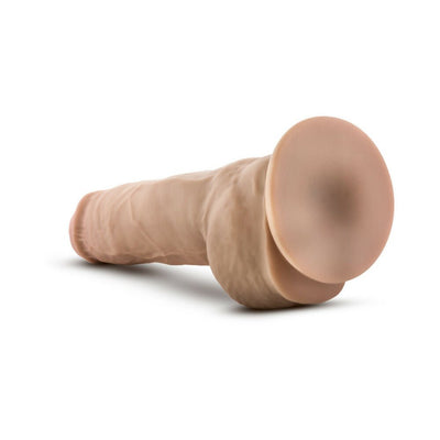 Realistic beige dual density dildo with suction cup base lying on white background.