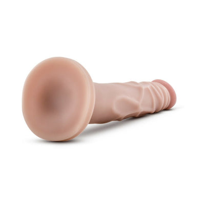 Flexible beige silicone dildo with suction cup base lying on white surface.