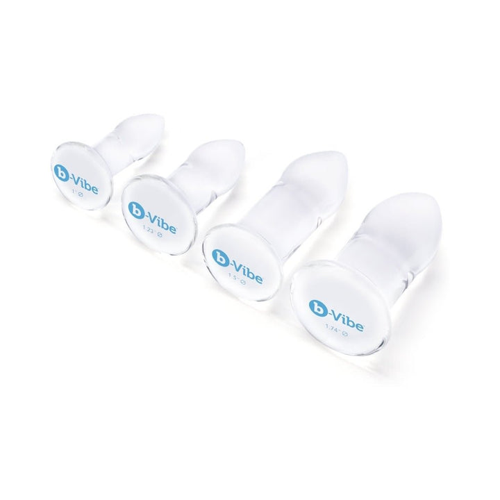 Set of four clear glass anal dilators in graduated sizes with rounded tips and flat bases, branded b-Vibe.