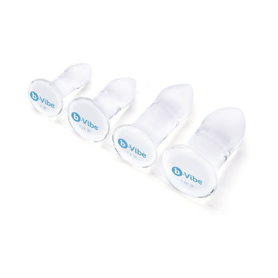 Set of four clear glass anal dilators in graduated sizes with rounded tips and flat bases, branded b-Vibe.
