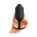 Hand holding a large black silicone weighted plug with a tapered base and smooth handle.